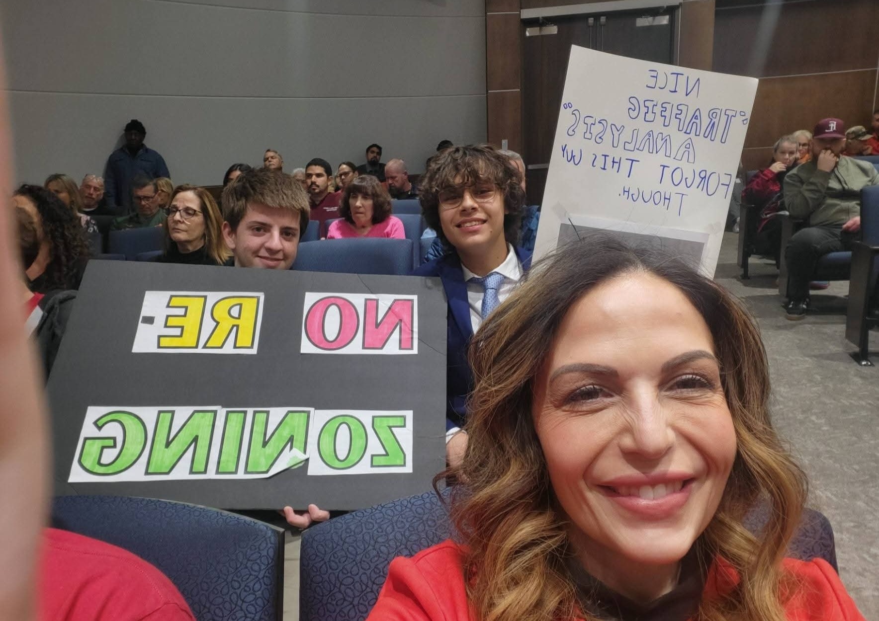 Niccole Pazos standing with neighbors holding signs opposing a hotel development